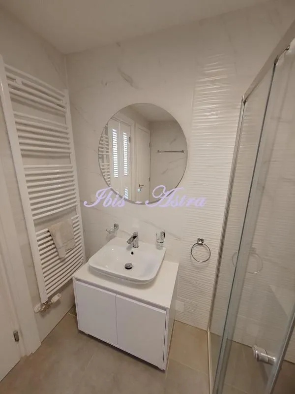 Modern bathroom equipped with a washbasin, mirror, and shower cabin.