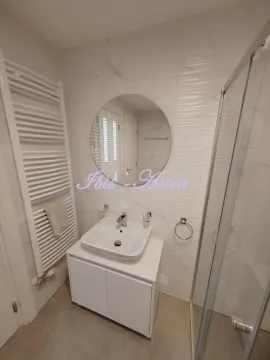 Modern bathroom equipped with a washbasin, mirror, and shower cabin. - image 11