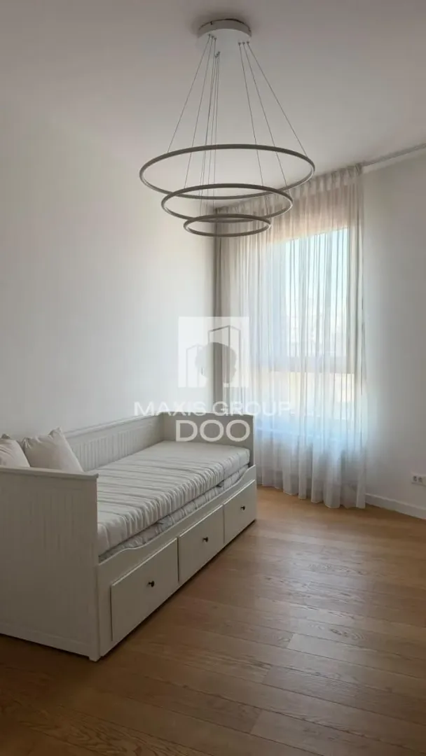 Manja spavaća soba sa krevetom i modernim lusterom.