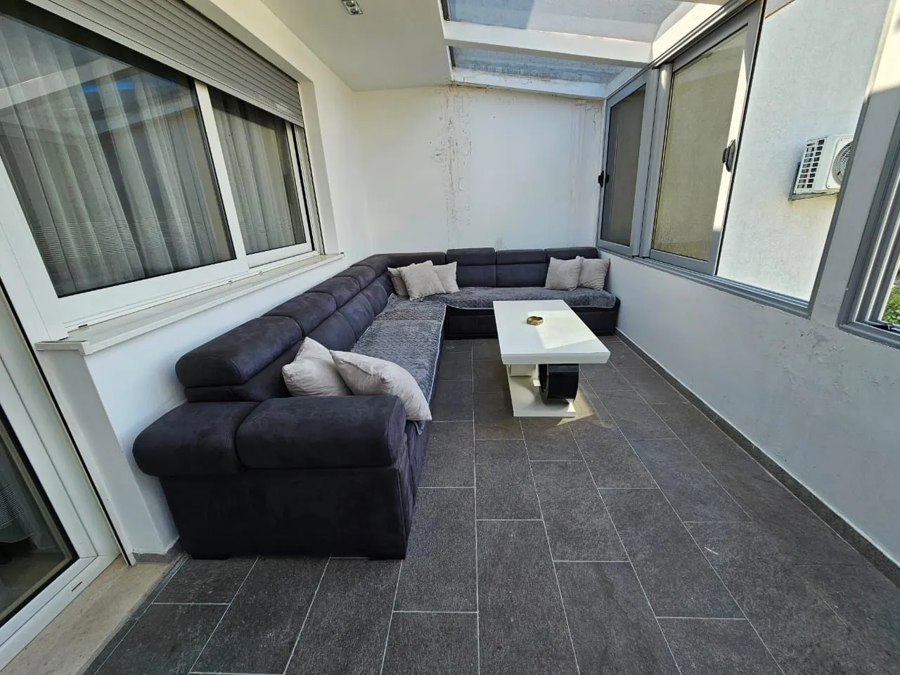 Enclosed living room with a sofa set and a glass roof.