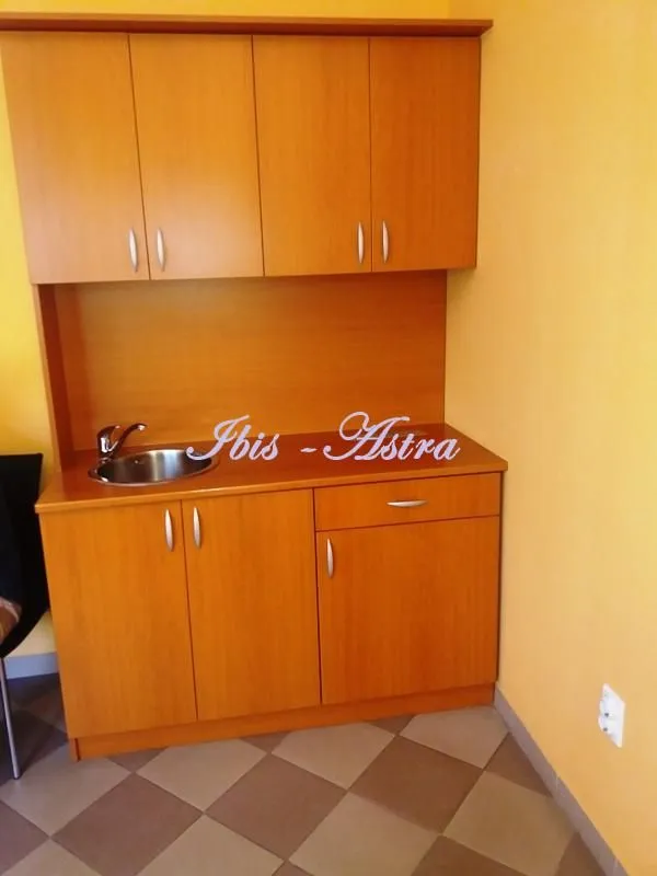 Small wooden kitchenette with a built-in sink and cabinets.