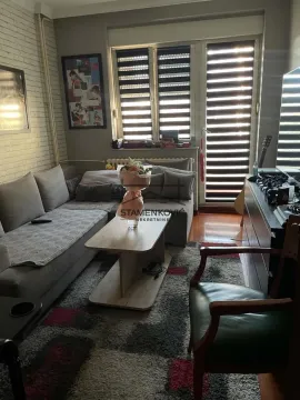 Dnevna soba sa ugaonom garniturom, stočićem i prozorima sa roletnama. - image 12