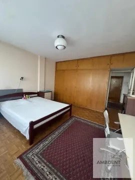 Nameštena spavaća soba sa bračnim krevetom, velikim drvenim ormarom i tepihom. - image 9