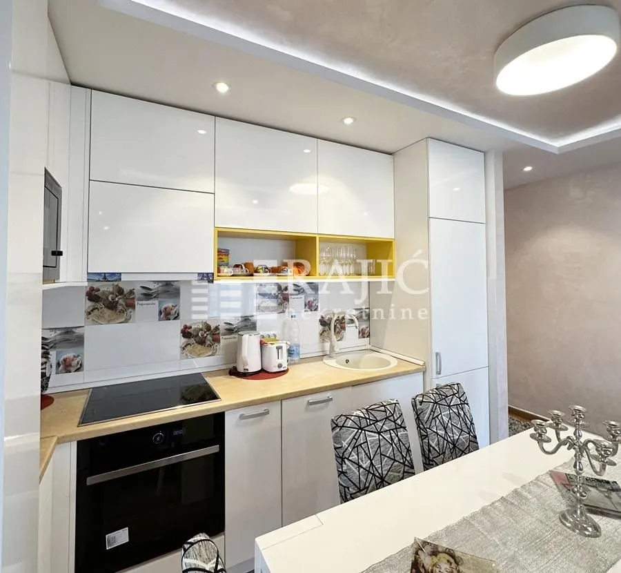Modern white kitchen with built-in appliances and a dining table.