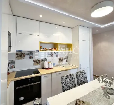 Modern white kitchen with built-in appliances and a dining table. - image 9