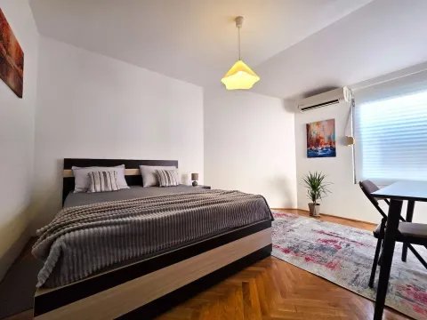 Spacious bedroom with a double bed, parquet flooring, and a dining table. - image 15