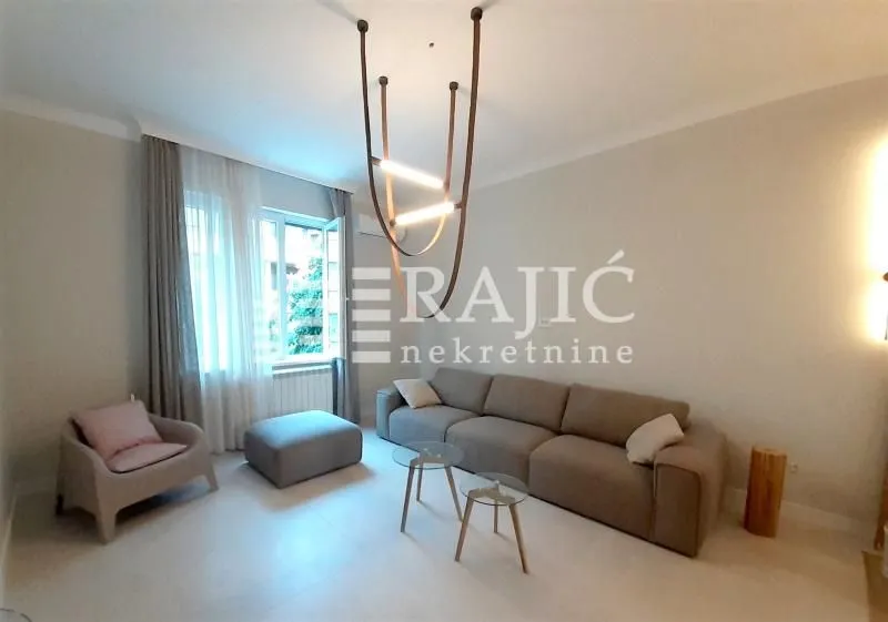 Living room with a sofa, armchair, and modern chandelier.