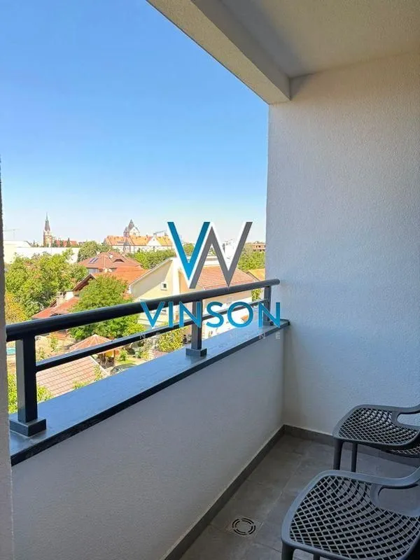 Natkriveni balkon sa pogledom na grad i stambene objekte.