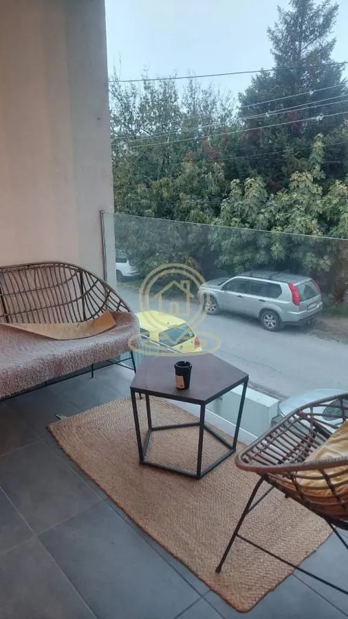 Namešten balkon sa garniturom za sedenje i pogledom na ulicu.