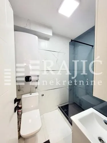 Modern bathroom with a shower cabin, toilet, and water heater.