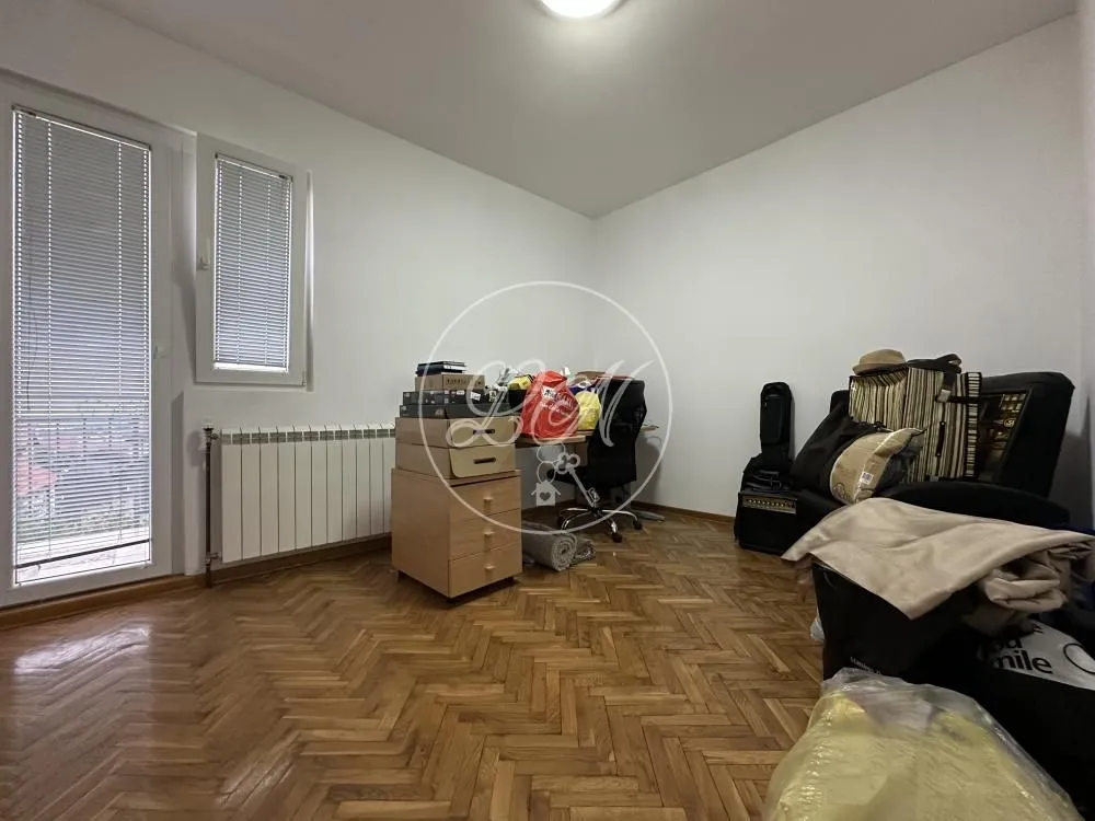 Small room with parquet flooring, furniture, and balcony doors.