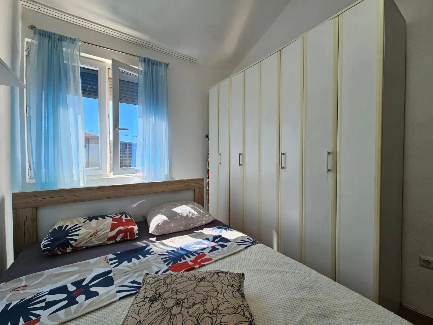 Bedroom with a double bed, window, and a large built-in wardrobe.