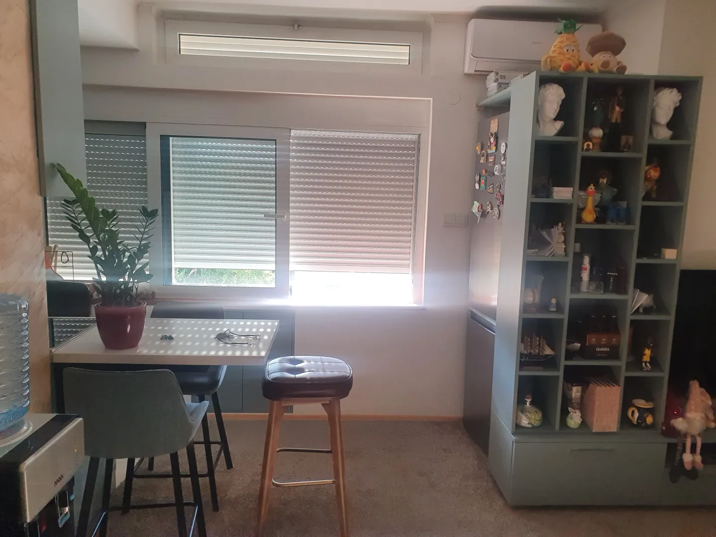 Dnevni boravak sa trpezarijskim stolom, policama i prozorom.