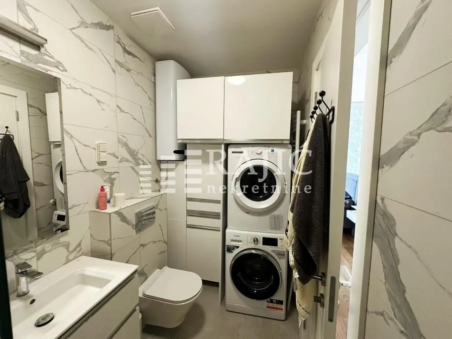 Modern bathroom with a sink, toilet, washing machine, and built-in cabinets.