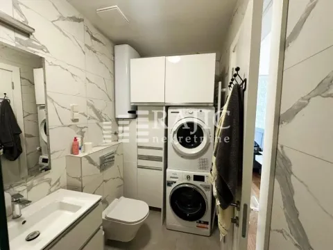 Modern bathroom with a sink, toilet, washing machine, and built-in cabinets. - image 8