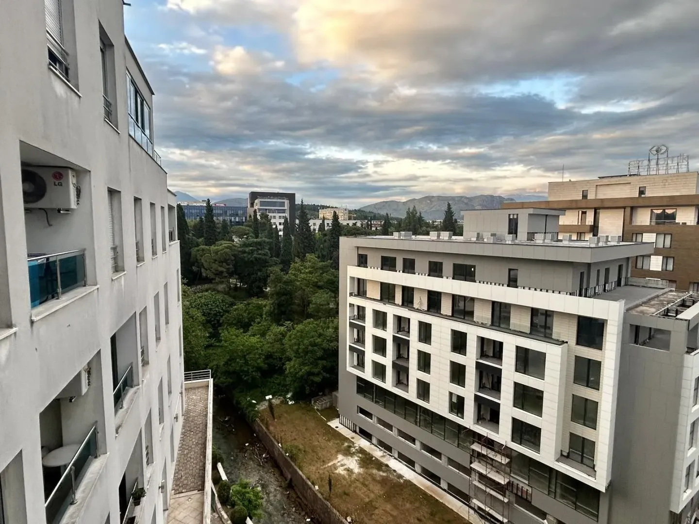 A view from the window of surrounding buildings and a green area.