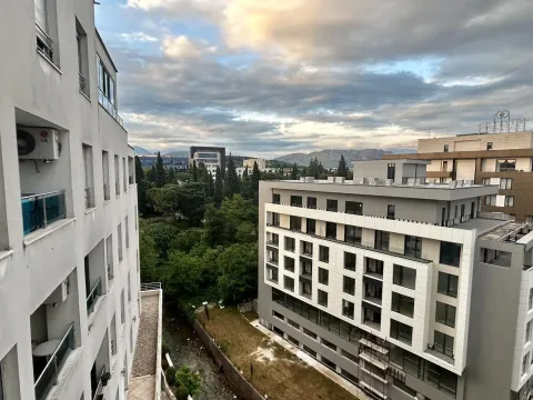 A view from the window of surrounding buildings and a green area. - image 18