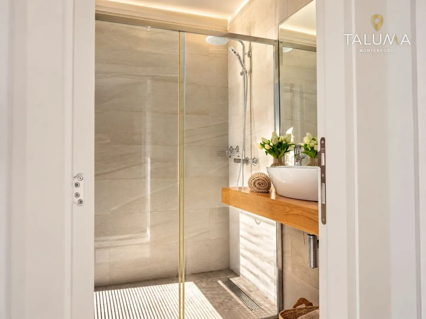 Modern bathroom with a walk-in shower and a washbasin on a wooden shelf.