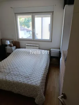Nameštena spavaća soba sa bračnim krevetom, prozorom i noćnim stočićima. - image 9