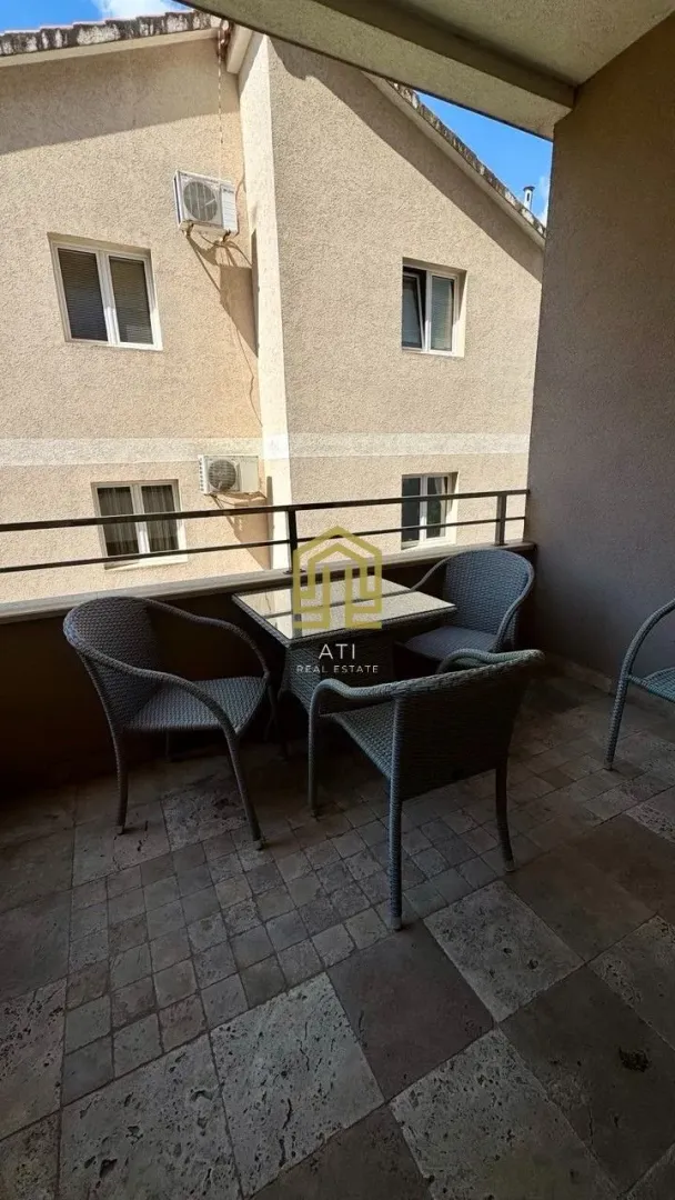 Natkrivena terasa sa garniturom za sjedenje i pogledom na susjednu zgradu.