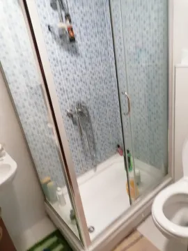 Kupatilo sa staklenom tuš kabinom i plavim mozaik pločicama. - image 9