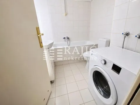 Smaller bathroom with a bathtub, washbasin, and washing machine. - image 7