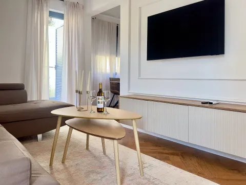 Dnevna soba sa garniturom, TV-om i stočićem sa flašom vina i čašama. - image 2