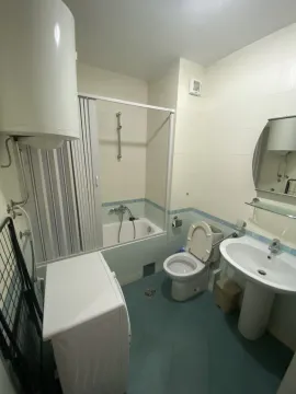 A functional bathroom featuring a bathtub, washbasin, and a washing machine. - image 10