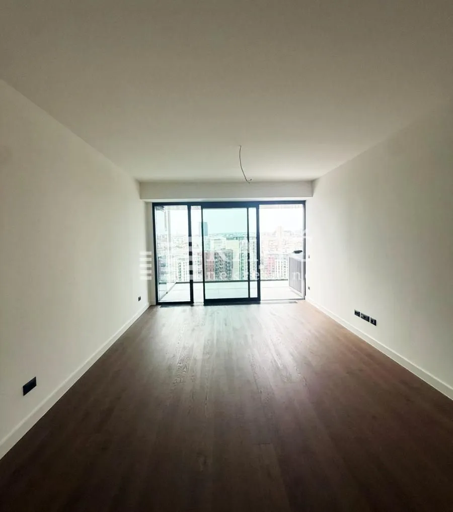 Empty living room with wooden flooring and access to the terrace.