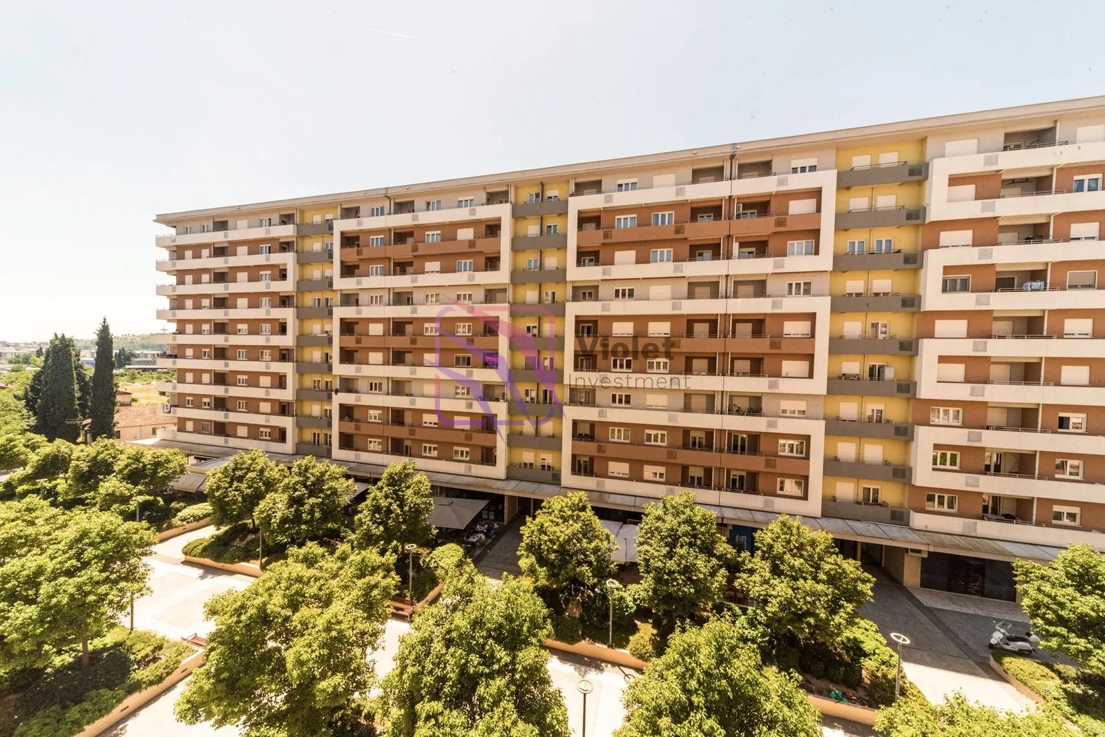 View of the facade of a modern residential building with a landscaped courtyard and greenery.