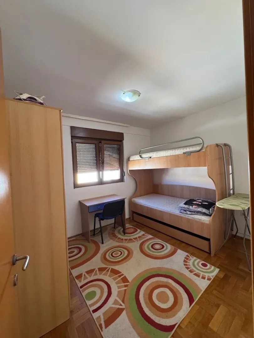 Children's bedroom with a bunk bed, desk, and wardrobe.