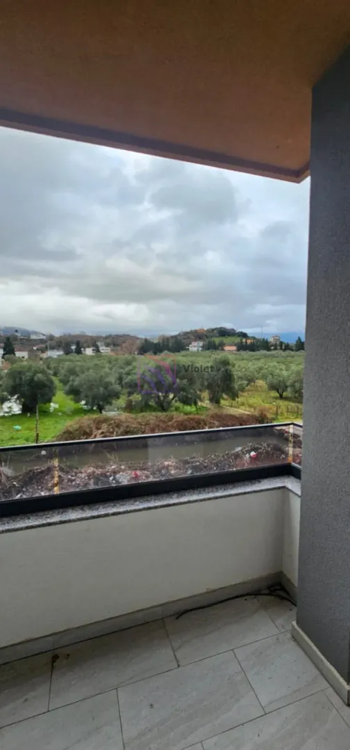 Pogled sa balkona na zelenu površinu i okolni pejzaž.