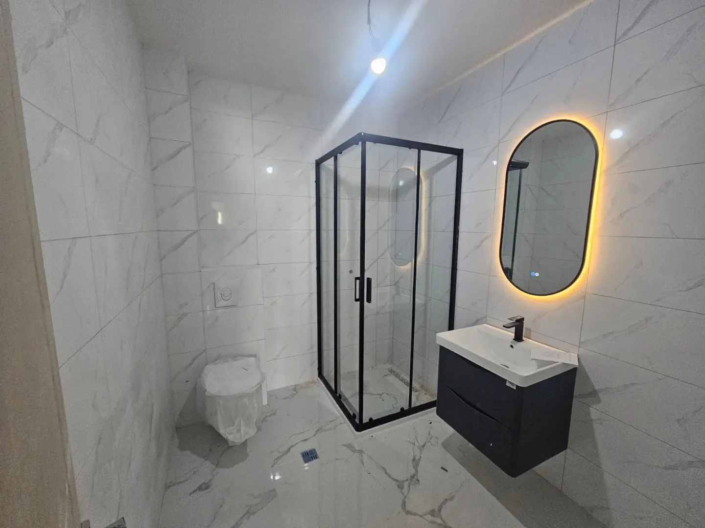 Moderne opremljeno kupatilo sa tuš kabinom i umivaonikom.
