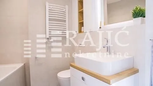 Modernly equipped bathroom with a washbasin, shower, and toilet.