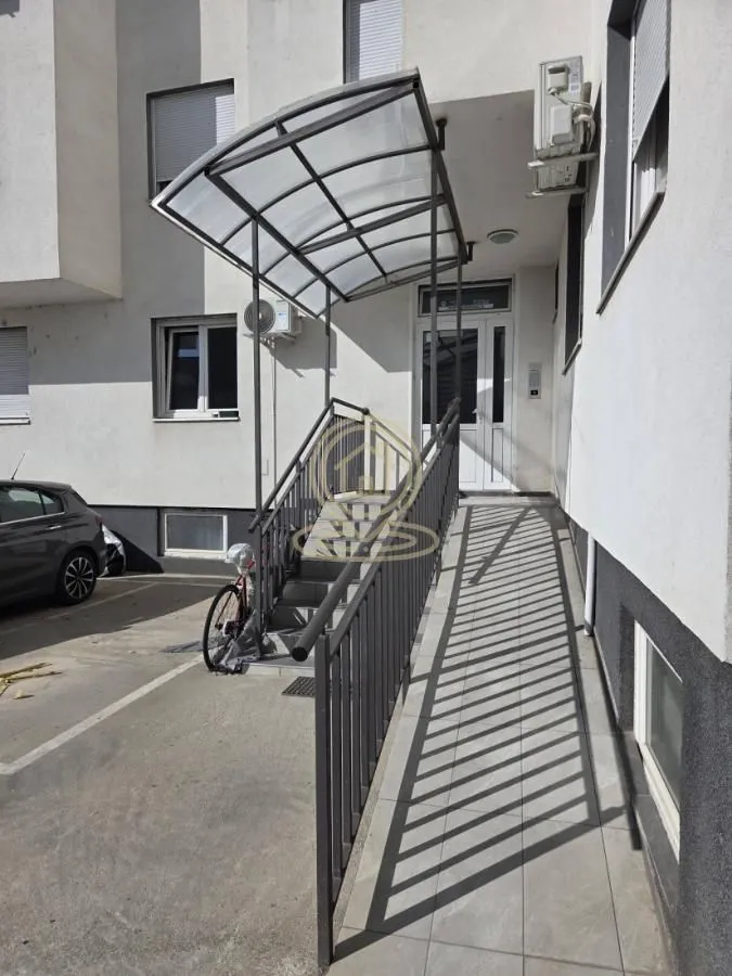 Ulaz u zgradu sa stepeništem, rampom i nadstrešnicom.