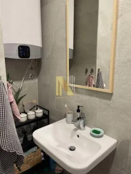 Small bathroom with a washbasin, mirror, and water heater. - image 6