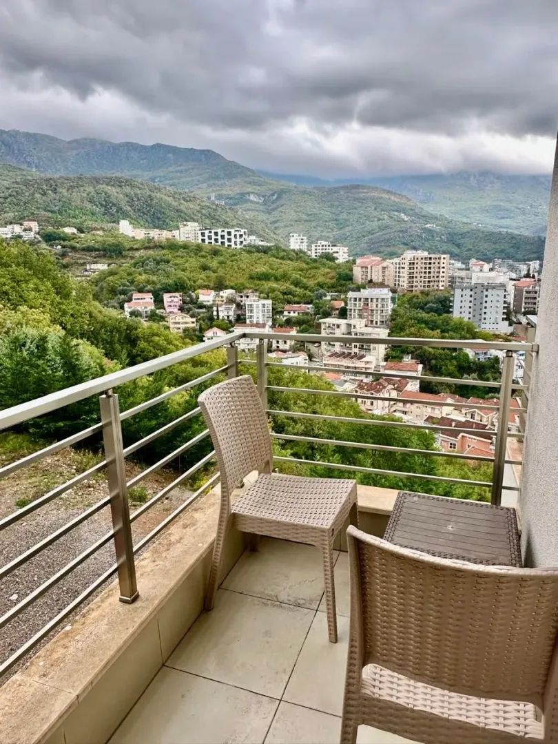 Furnished balcony with outdoor seating and a view of the city and mountains.