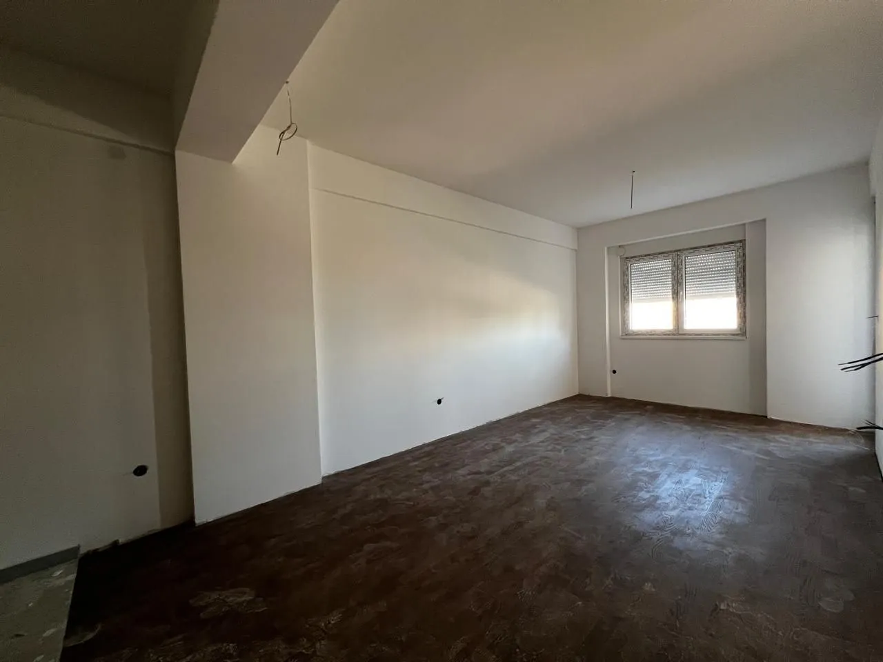 Neopremljena prostorija u fazi renoviranja sa bijelim zidovima i prozorom.