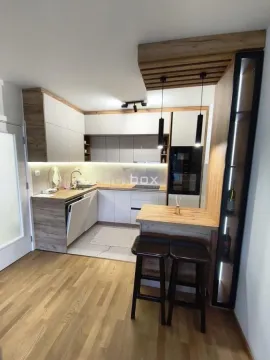 Moderna kuhinja sa drvenim elementima, ugradnim aparatima i šankom sa barskim stolicama. - image 3
