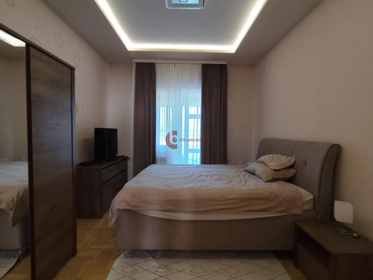 Furnished bedroom with a double bed, wardrobe, and TV unit.