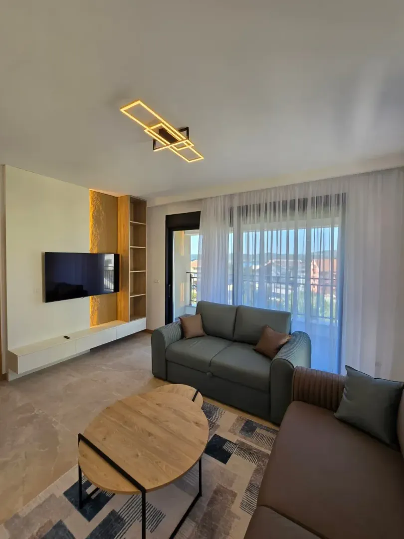 Modern living room with a sofa, TV, and access to the terrace.