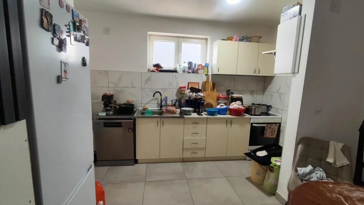 Manja kuhinja sa elementima i tehnikom, vidljivi su tragovi svakodnevne upotrebe i nered.