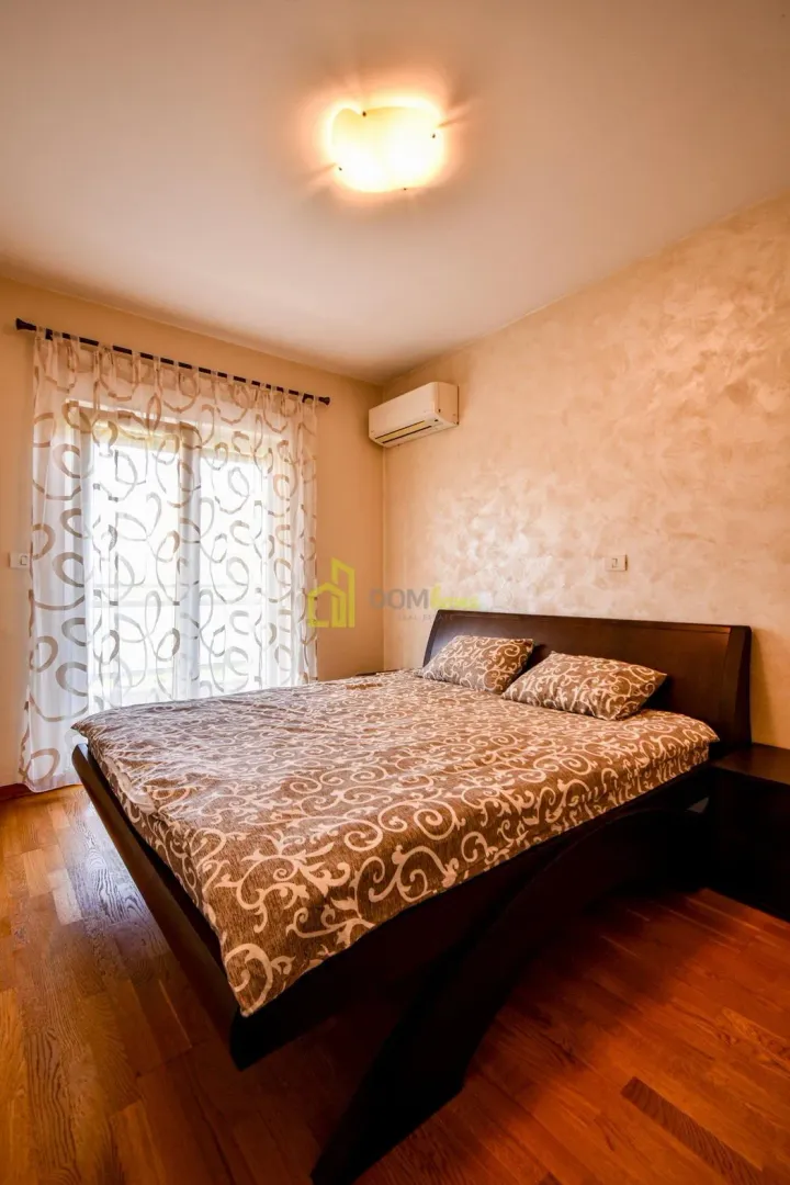 Furnished bedroom with a double bed, wooden flooring, and balcony access.