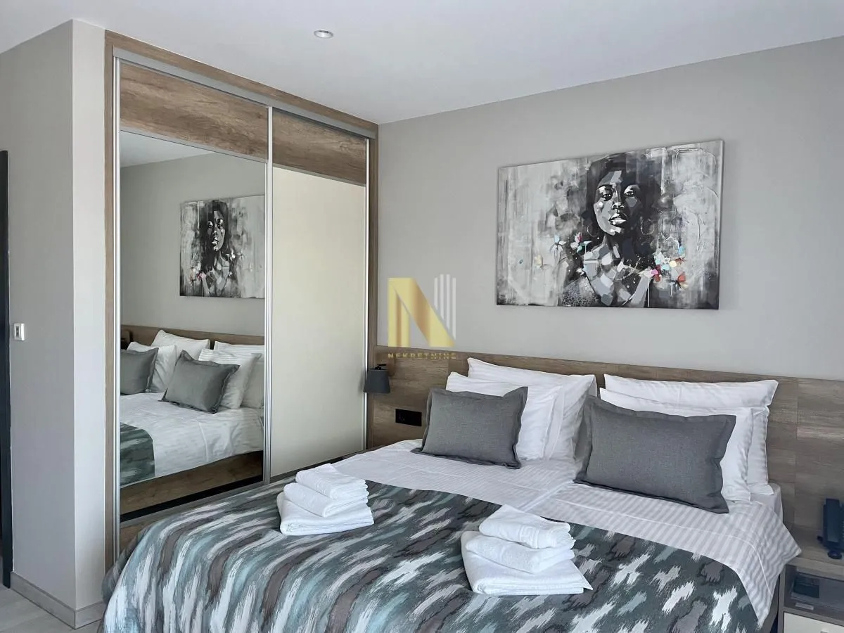 Furnished bedroom with a double bed, mirrored wardrobe, and wall art.