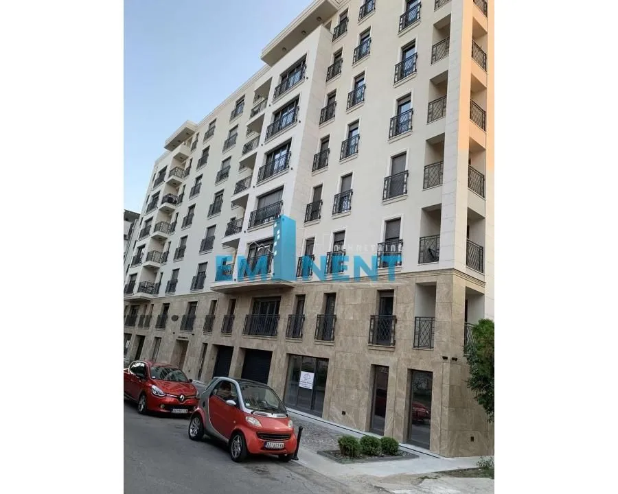 Exterior view of a modern residential building with parked cars on the street.