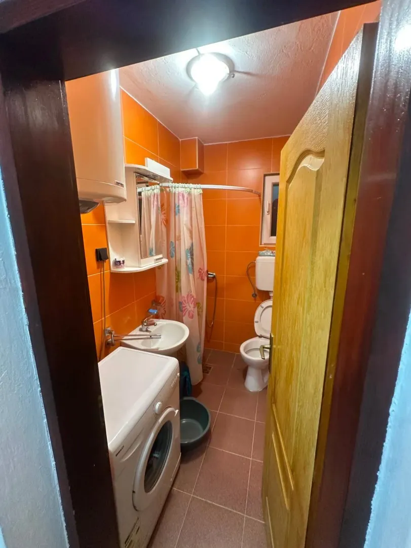 Small bathroom with orange tiles, sanitary ware, and a washing machine.