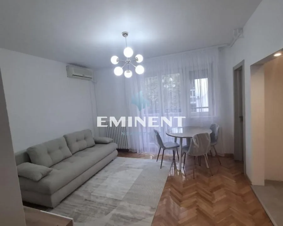 Living room with a sofa, dining table, and parquet flooring.