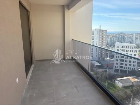Nenamješten balkon sa staklenom ogradom i pogledom na grad. - image 2