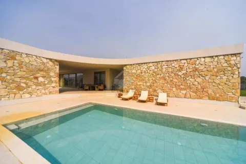 Swimming pool with a sun terrace and sun loungers in front of a modern house with a stone facade. - image 3