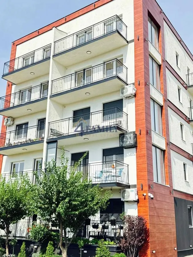 Spoljašnji izgled višestambene zgrade sa terasama i drvećem u dvorištu.
